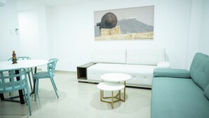 A modern living room with a white sofa, teal chairs, a small white table, and a painting on the wall. - Apartment 5B Minaret (Bolívar)