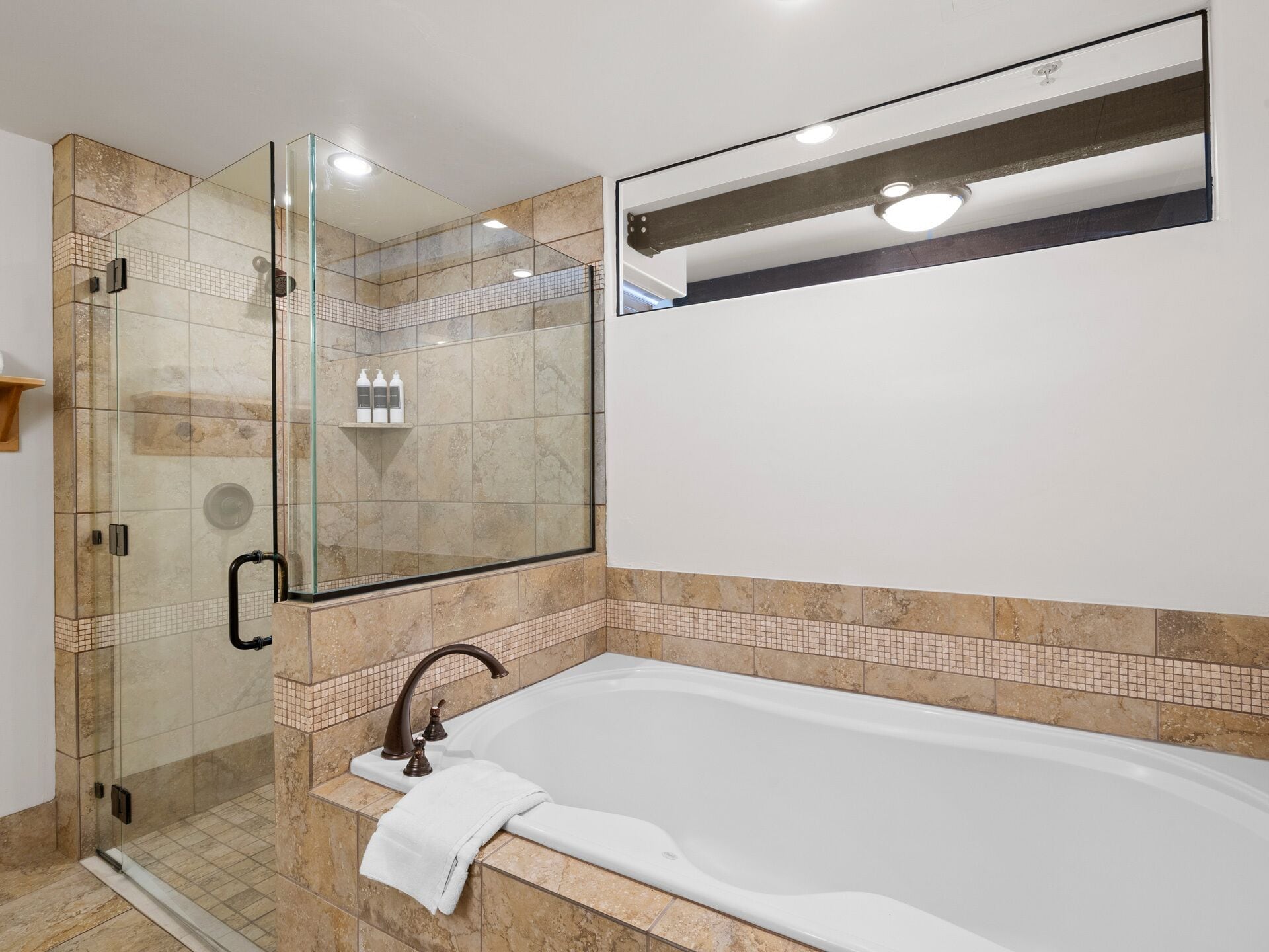 A modern bathroom with a glass-enclosed shower, a large bathtub, and a mirror above the sink.