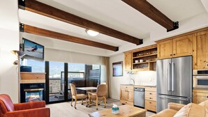 Una sala de estar moderna con chimenea, un comedor y una cocina con armarios de madera y electrodomésticos de acero inoxidable.