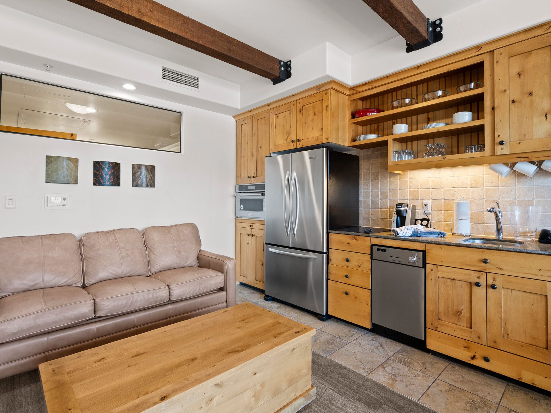 Une cuisine moderne avec des meubles en bois, des appareils en acier inoxydable et un canapé en cuir beige.
