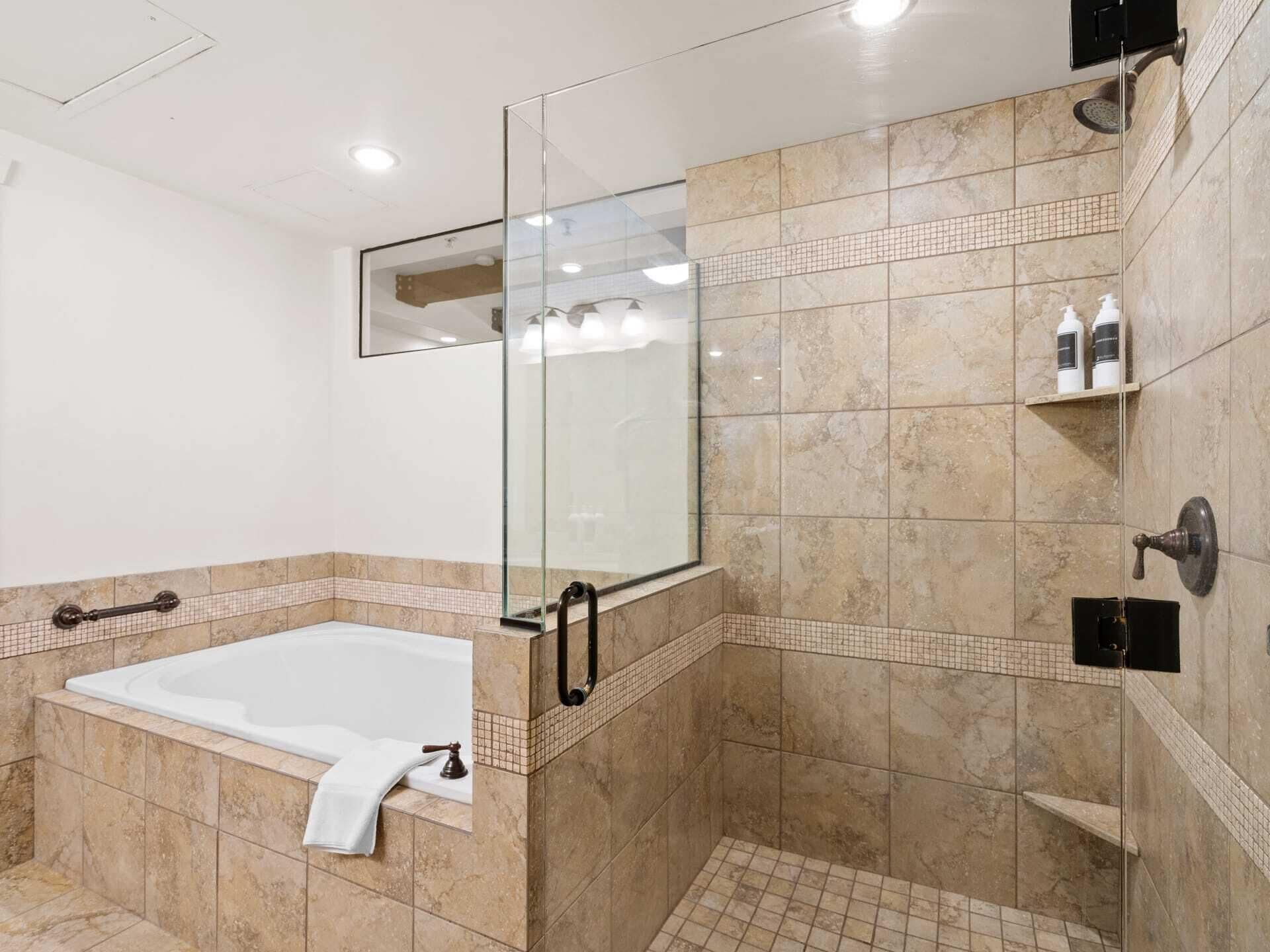 Un baño moderno con ducha de vidrio, bañera independiente y zona de ducha con azulejos.