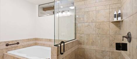Un baño moderno con ducha de vidrio, bañera independiente y zona de ducha con azulejos.