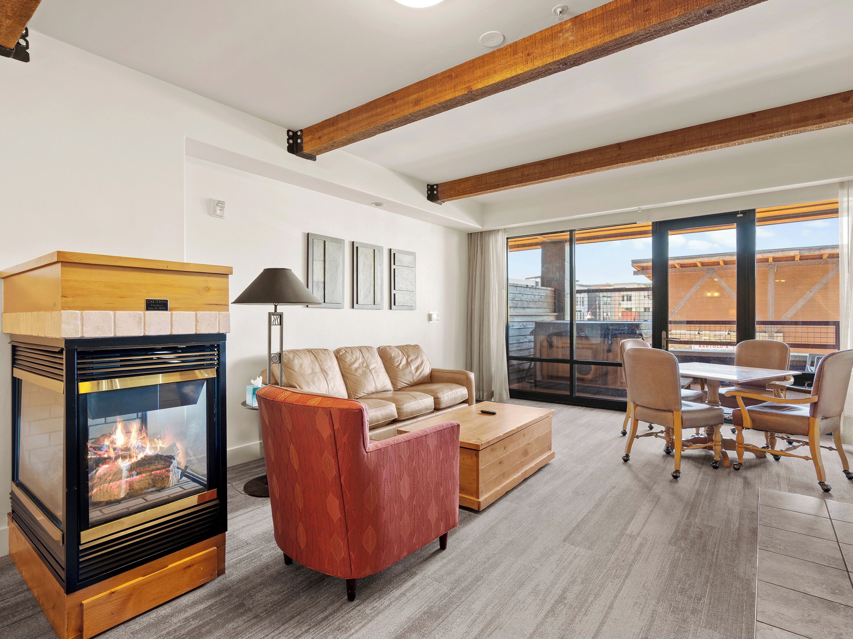 A living room with a fireplace, leather sofa, and a dining area with chairs and a table.