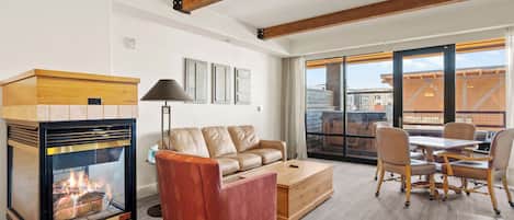A living room with a fireplace, leather sofa, and a dining area with chairs and a table.