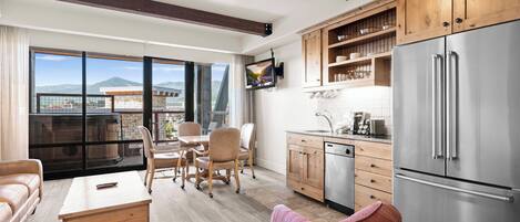 A modern kitchen with wooden cabinets, a stainless steel refrigerator, and a dining area with a table and chairs.