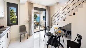 A modern kitchen with a dining area, a staircase, and a view of the sea. - N&G Deluxe Maisonette (Lefkada)