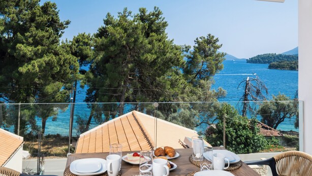 A dining table set for breakfast with a view of the sea and trees. - N&G Deluxe Maisonette (Lefkada)