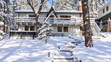A snow-covered building with a balcony, a staircase, and a bench.