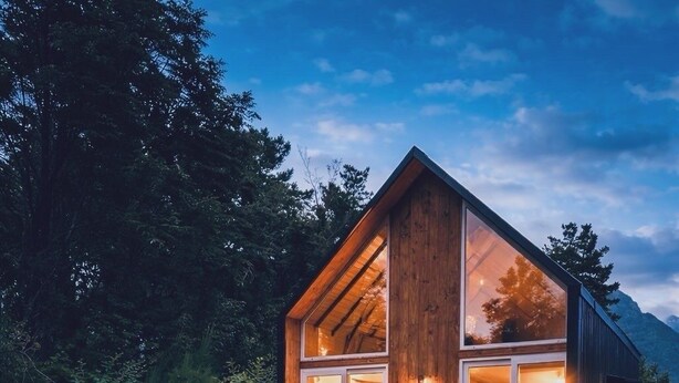 Une cabane en bois dotée d’une terrasse, d’un foyer et d’un espace repas.