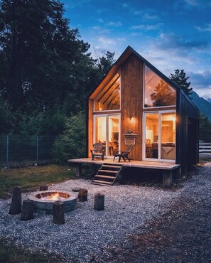 A wooden cabin with a deck, a fire pit, and a dining area. - Almabosque Pucón (Pucón)