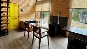 Un intérieur en bois avec une porte jaune, une cheminée et un coin repas avec des chaises.