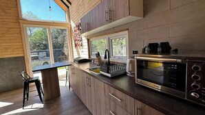 Une cuisine moderne avec des meubles en bois, un four encastré et une grande fenêtre qui laisse entrer la lumière naturelle.