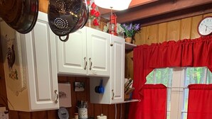 A kitchen with white cabinets, a stove, and a red window valance.