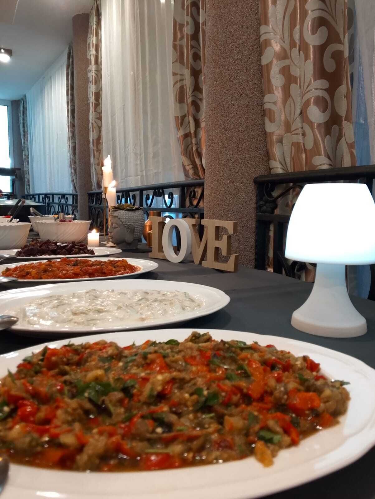 A dining table with various dishes, a candle, and the word 'LOVE' in the background.
