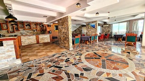 Un restaurant doté d’un sol en mosaïque, de murs en pierre et de meubles en bois.
