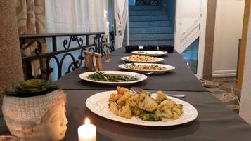 A dining table with plates of food, a candle, and a Buddha statue.