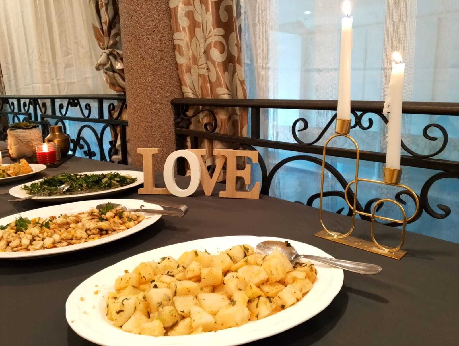 Une table à manger avec des assiettes remplies de nourriture, un chandelier et un mot décoratif, le mot « AMOUR », posé sur la table.