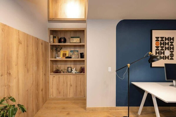 A room with a wooden cabinet, a desk with a computer, and a blue accent wall.