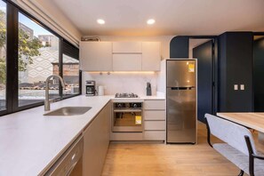 A modern kitchen with a built-in oven, a stainless steel refrigerator, and a window providing a view of the outside.