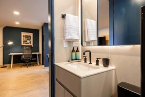 A modern bathroom with a white sink, a large mirror, and a towel hanging on the wall.