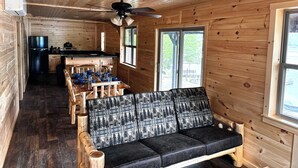 Interior de una cabaña de madera con comedor, sofá y cocina.