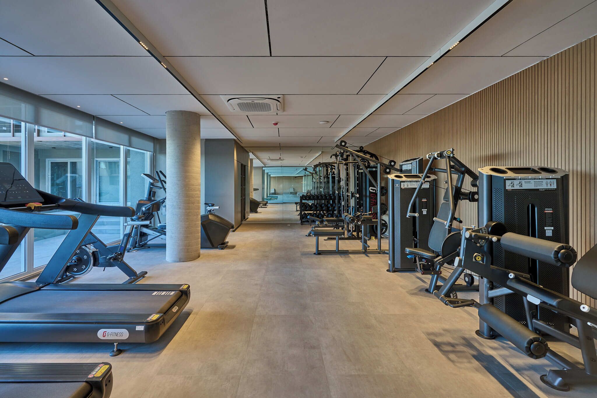 Une salle de sport moderne équipée de tapis de course, d’appareils de musculation et de poids libres.