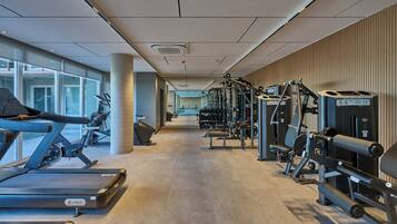Une salle de sport moderne équipée de tapis de course, d’appareils de musculation et de poids libres.