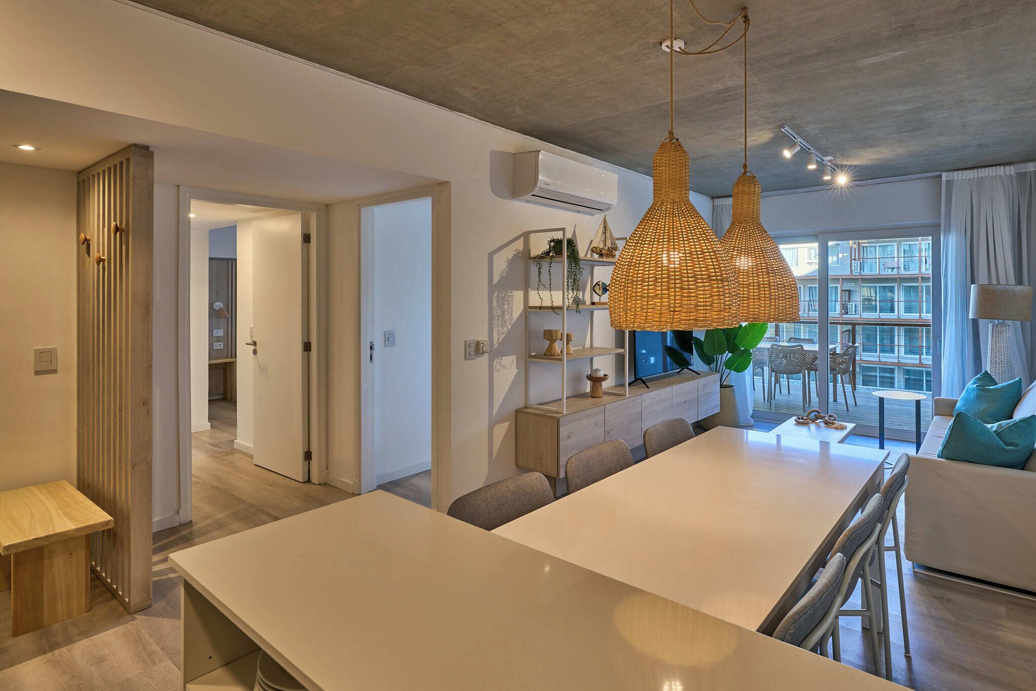 Cozinha moderna com ilha central, iluminação pendente e vista para a área de estar externa.