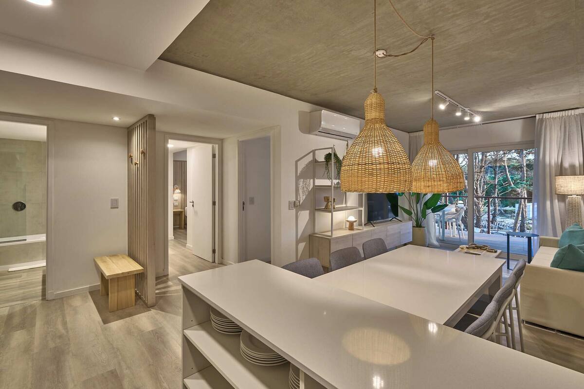 A modern kitchen with a large island, pendant lighting, and a view to the outdoors.