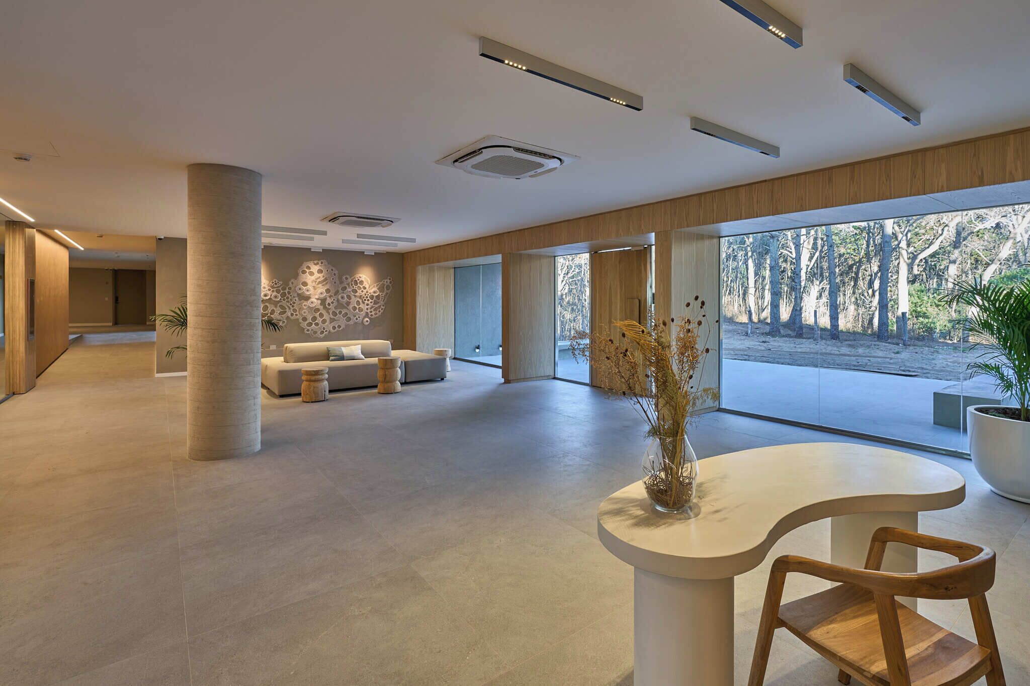 Un rebedor ampli amb un disseny modern, que destaca una zona de seients amb sofàs i una taula de cafè, una finestra gran que ofereix vistes a l'exterior, i un ram de flors decoratiu sobre una taula.