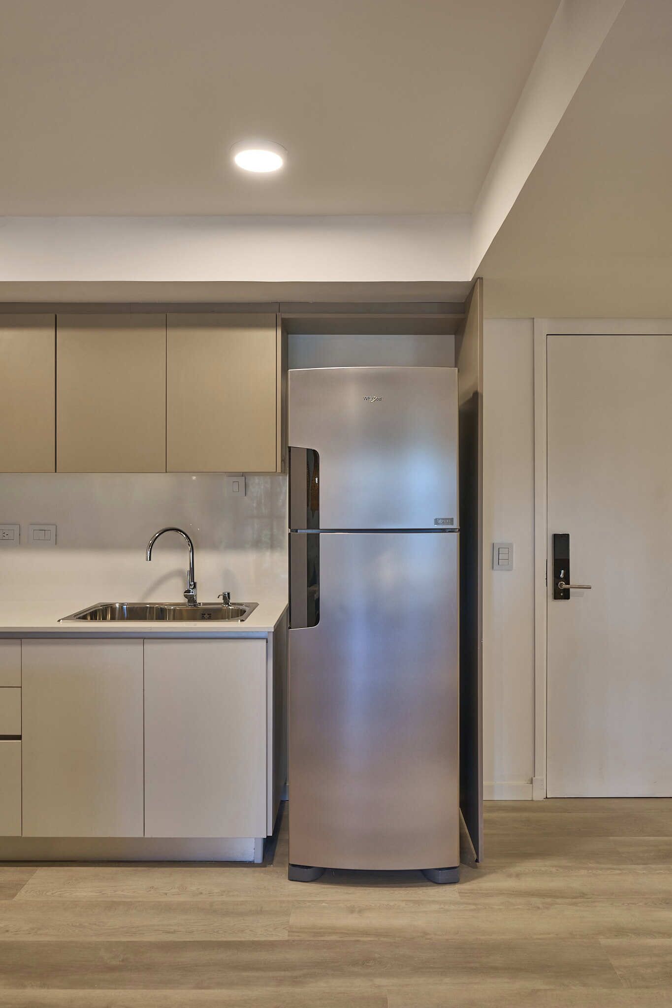 Een moderne keuken met een roestvrijstalen koelkast, een spoelbak en lichtgekleurde kasten.