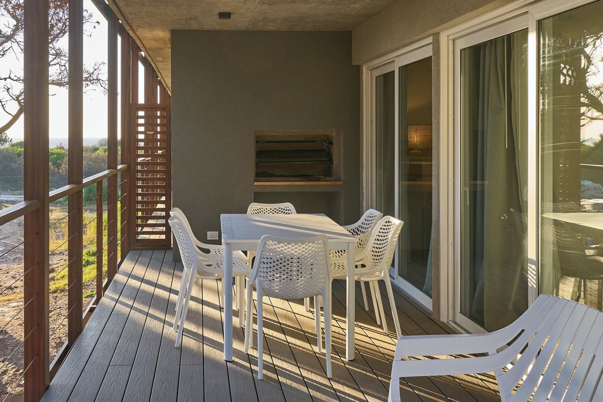 Un espacio al aire libre techado con una mesa y sillas, una terraza de madera y vistas del paisaje.