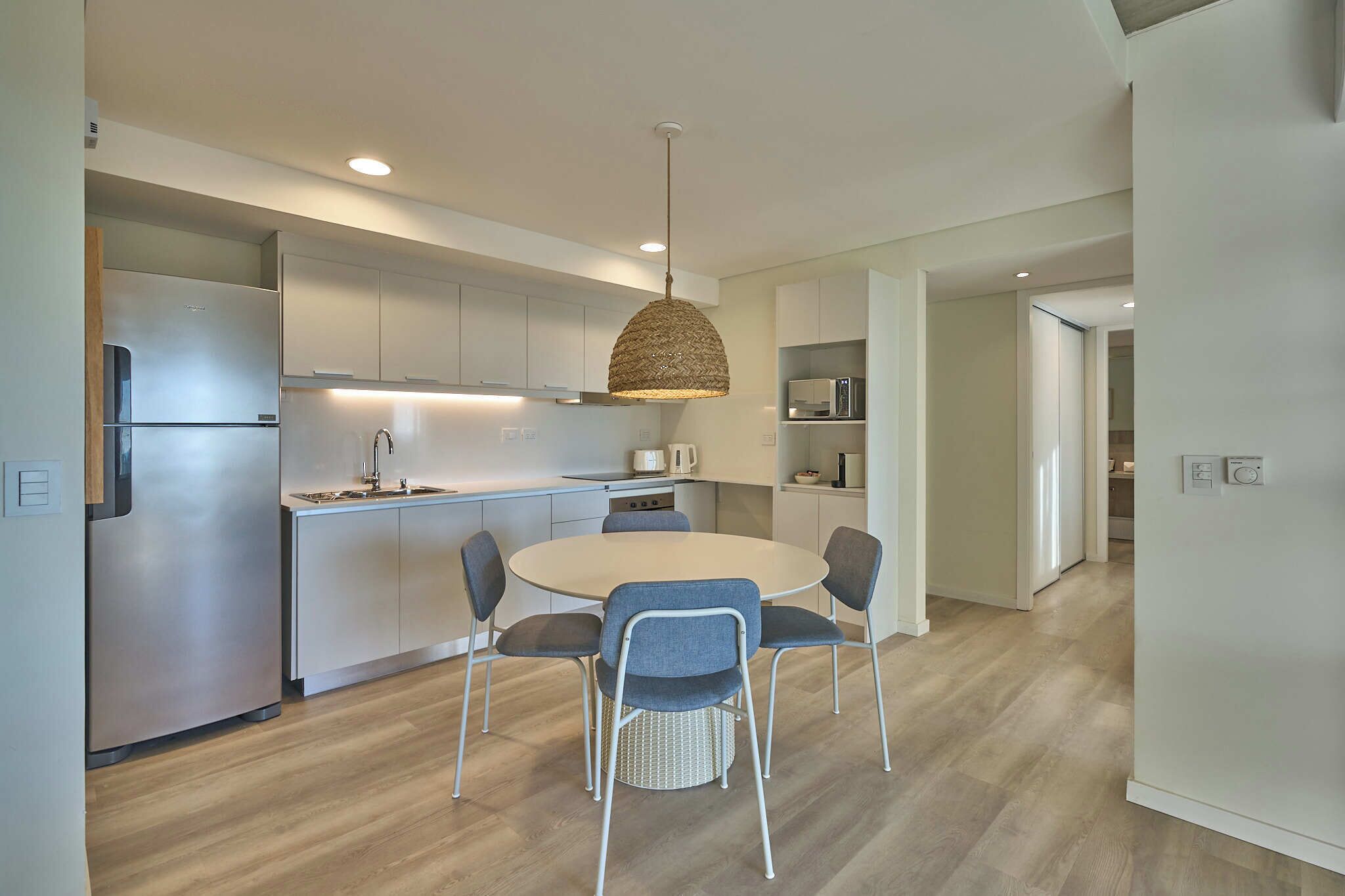 A modern kitchen with a central island, stainless steel appliances, and a hanging light fixture.