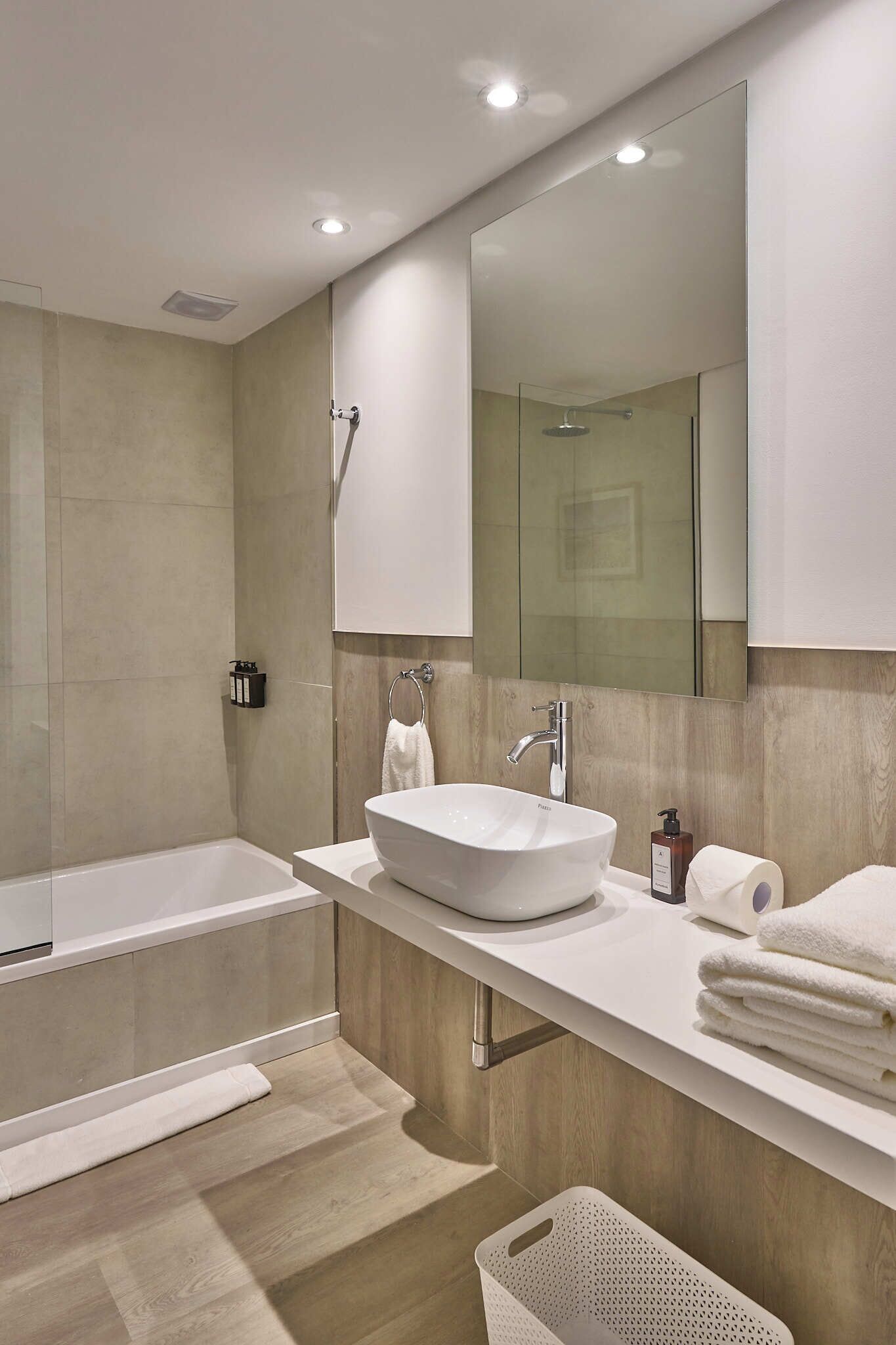 A modern bathroom with a large bathtub, a sink, and a mirror.