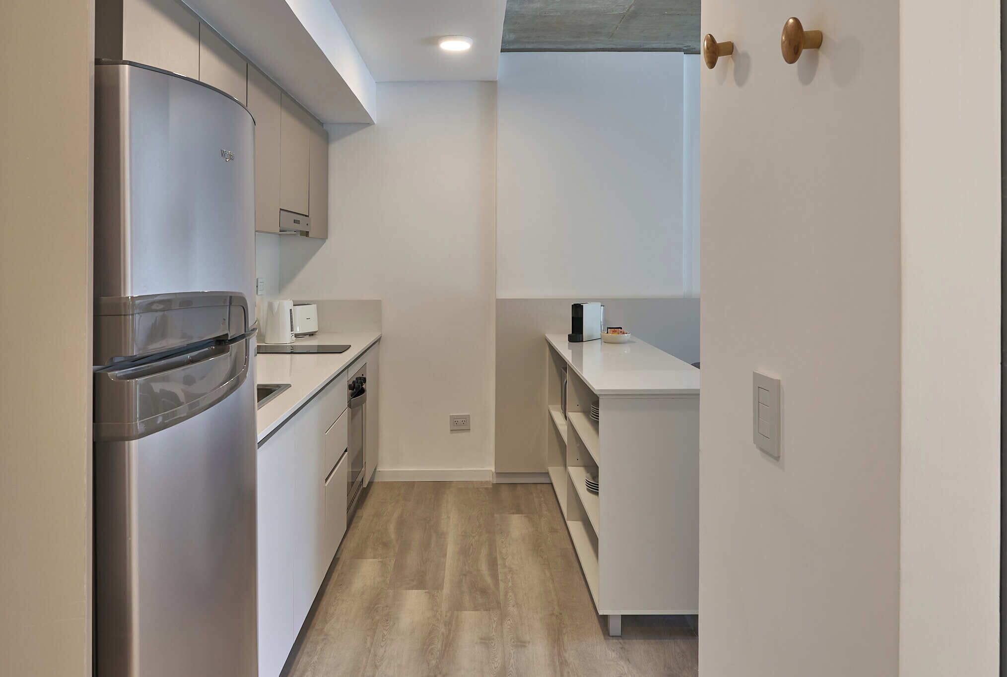 Una cocina compacta con refrigerador de acero inoxidable, un lavamanos y una encimera.