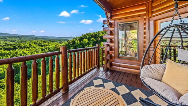 A wooden deck with a hanging chair and a view of a forested landscape. - Epic Views! + Hot Tub + 2 Kings + PS5 + Fire Pit (Sevierville)