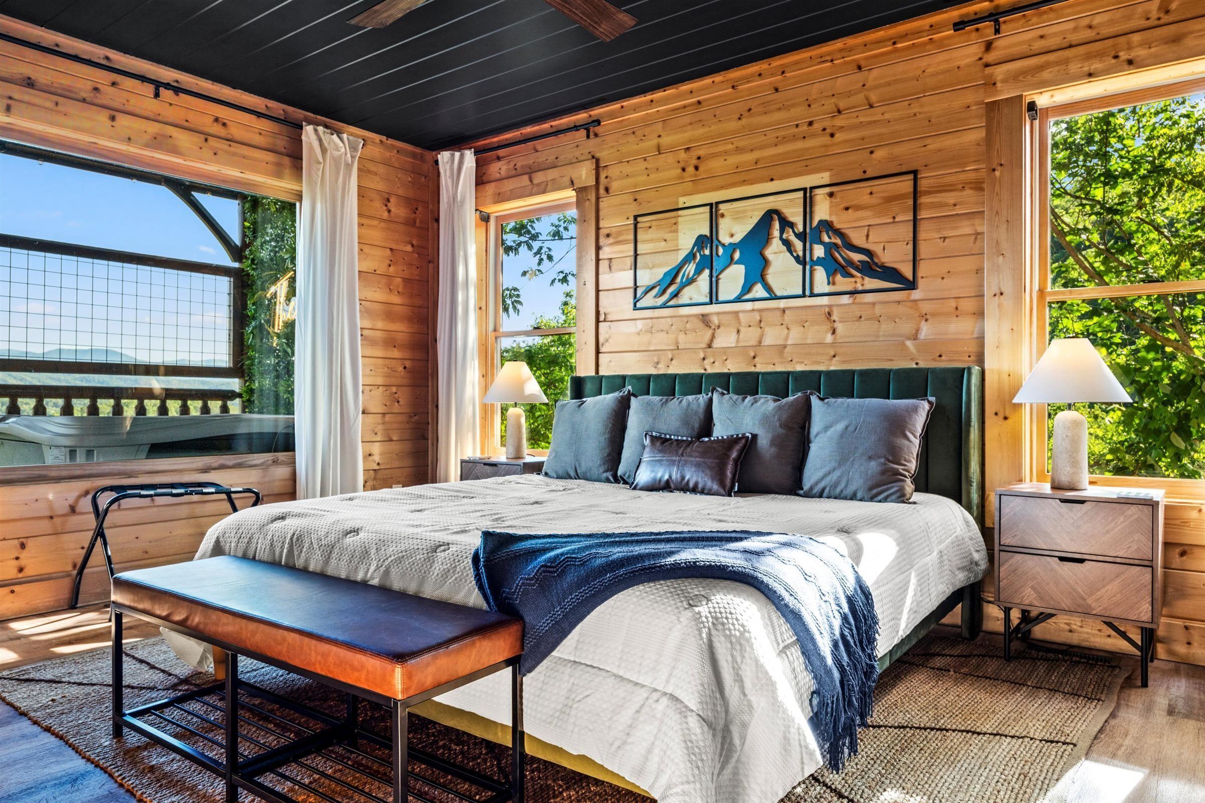 Een slaapkamer in een houten blokhut met een bed, een bankje, nachtkastjes en kunstwerken.