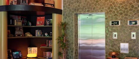 A modern interior with a curved bookshelf, a vintage television, and an elevator.
