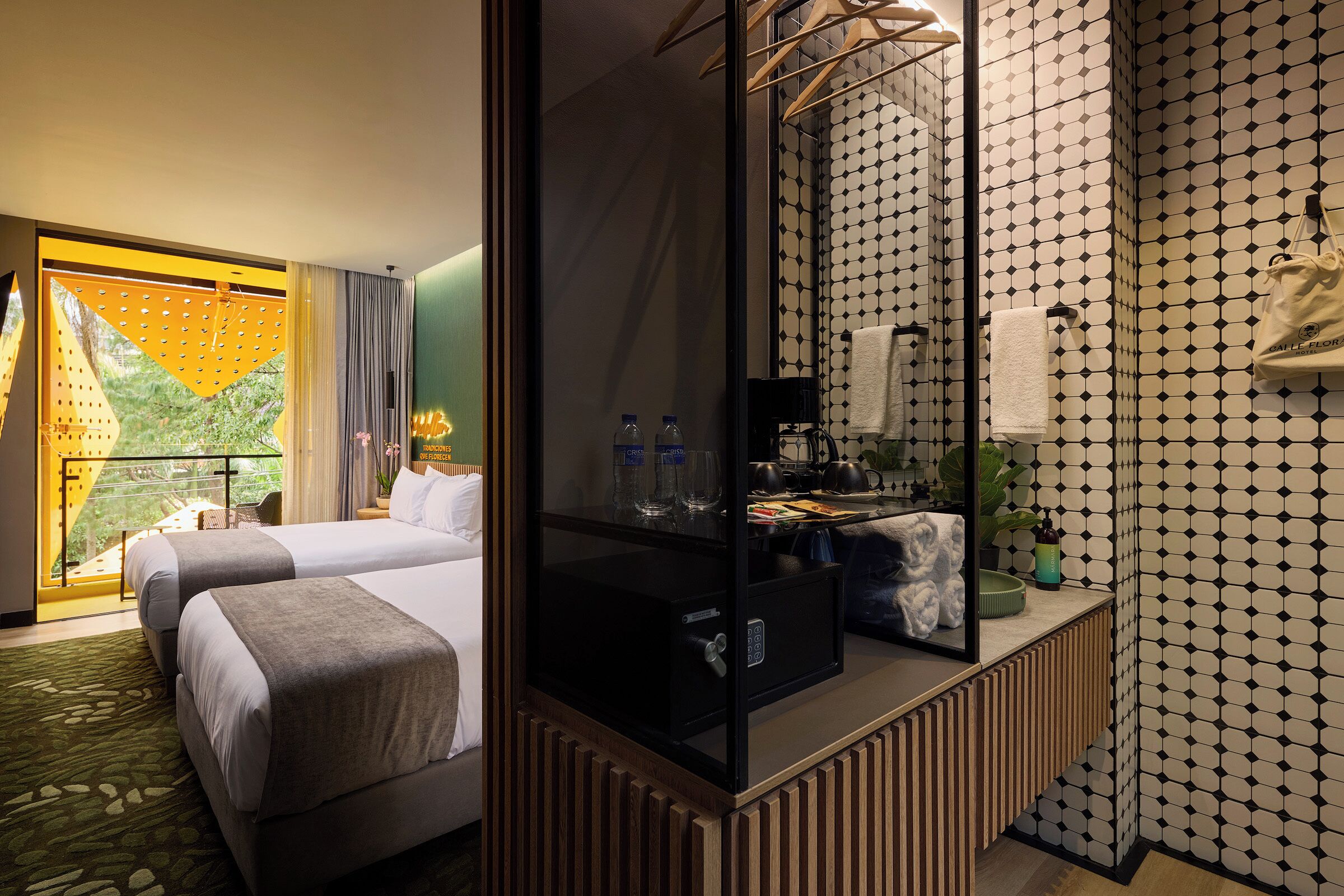 A hotel room with two beds, a minibar, a mirror, and a view of greenery.