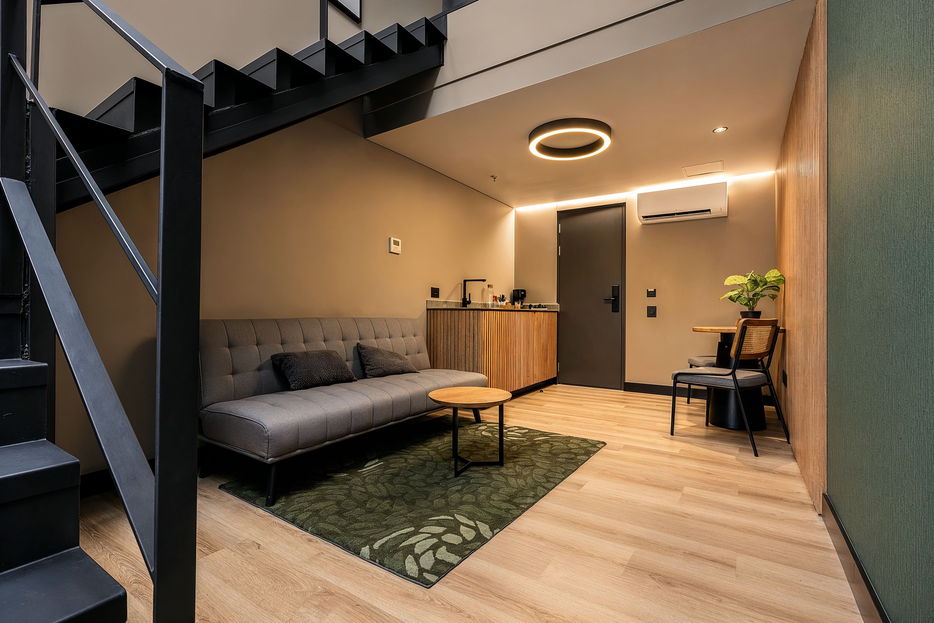 A modern living space with a staircase, a sofa, a coffee table, and a dining area.