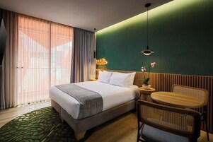 Ein Hotelzimmer mit einem Bett, einem kleinen Tisch, einem Stuhl und einer Zimmerpflanze.