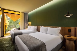 Une chambre d’hôtel avec deux lits, une tête de lit en bois, une petite table de chevet en bois, une grande fenêtre donnant sur un beau paysage et un mur vert.