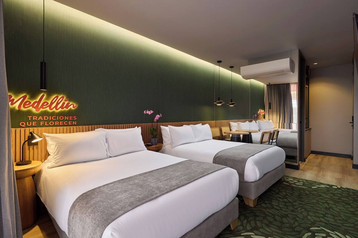 A hotel room with two beds, a desk, and a chair.