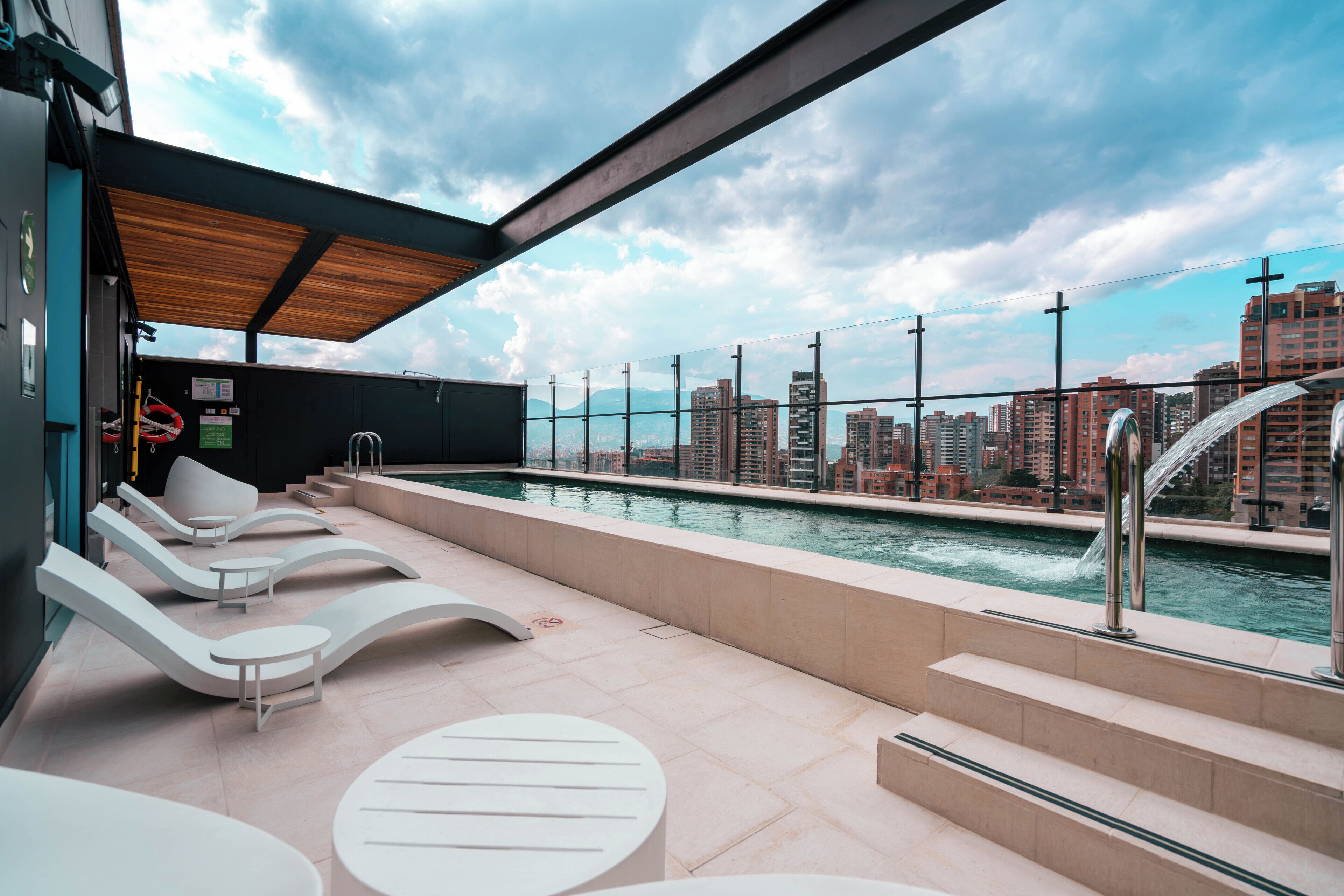 A rooftop pool area with lounge chairs and a view of the city skyline.