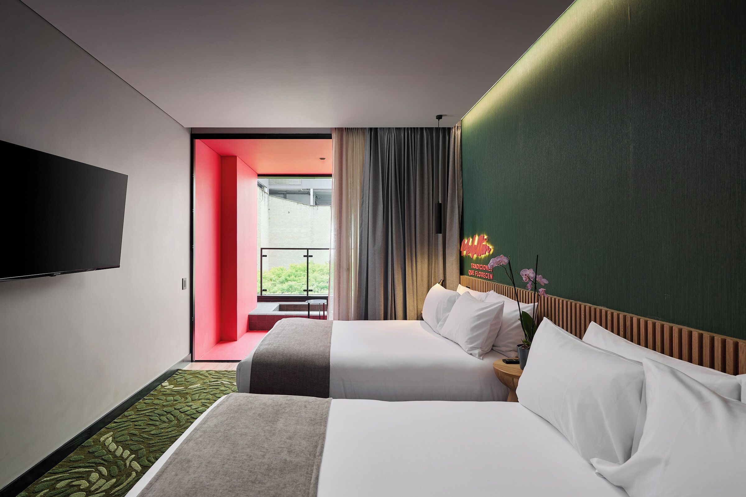 Habitación de hotel con dos camas, televisión de pantalla plana, vista al exterior y una pared de acento verde.