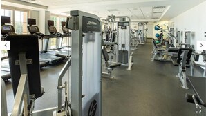 Un gimnasio con cintas de correr, máquinas de pesas y equipo cardiovascular.