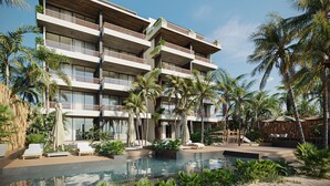 Un hotel de varios pisos con balcones, piscina y jardines tropicales.