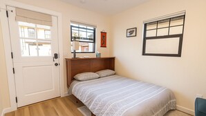 Ein Schlafzimmer mit einem Bett, einer Tür, einem Fenster und einem Wandbild.
