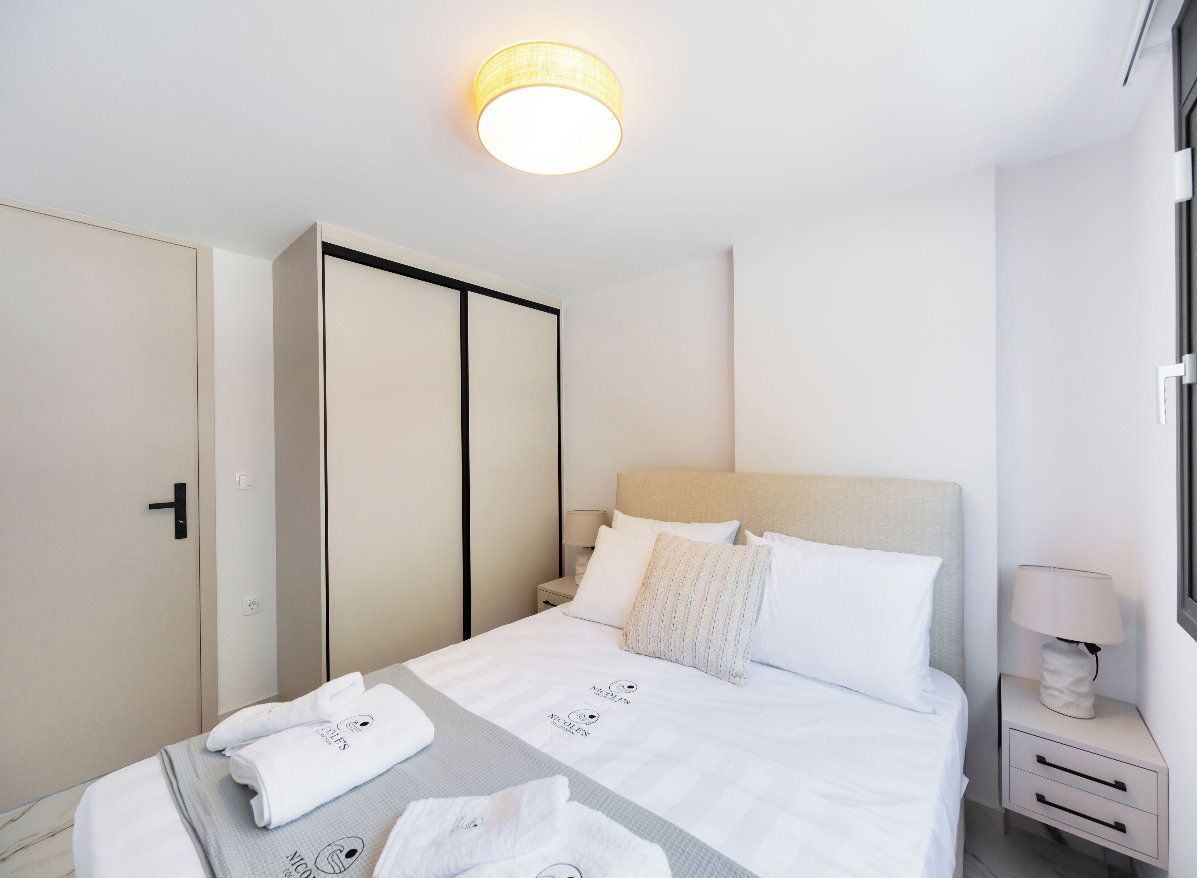 Une chambre d’hôtel avec un lit, une table de chevet, une armoire et une fenêtre.