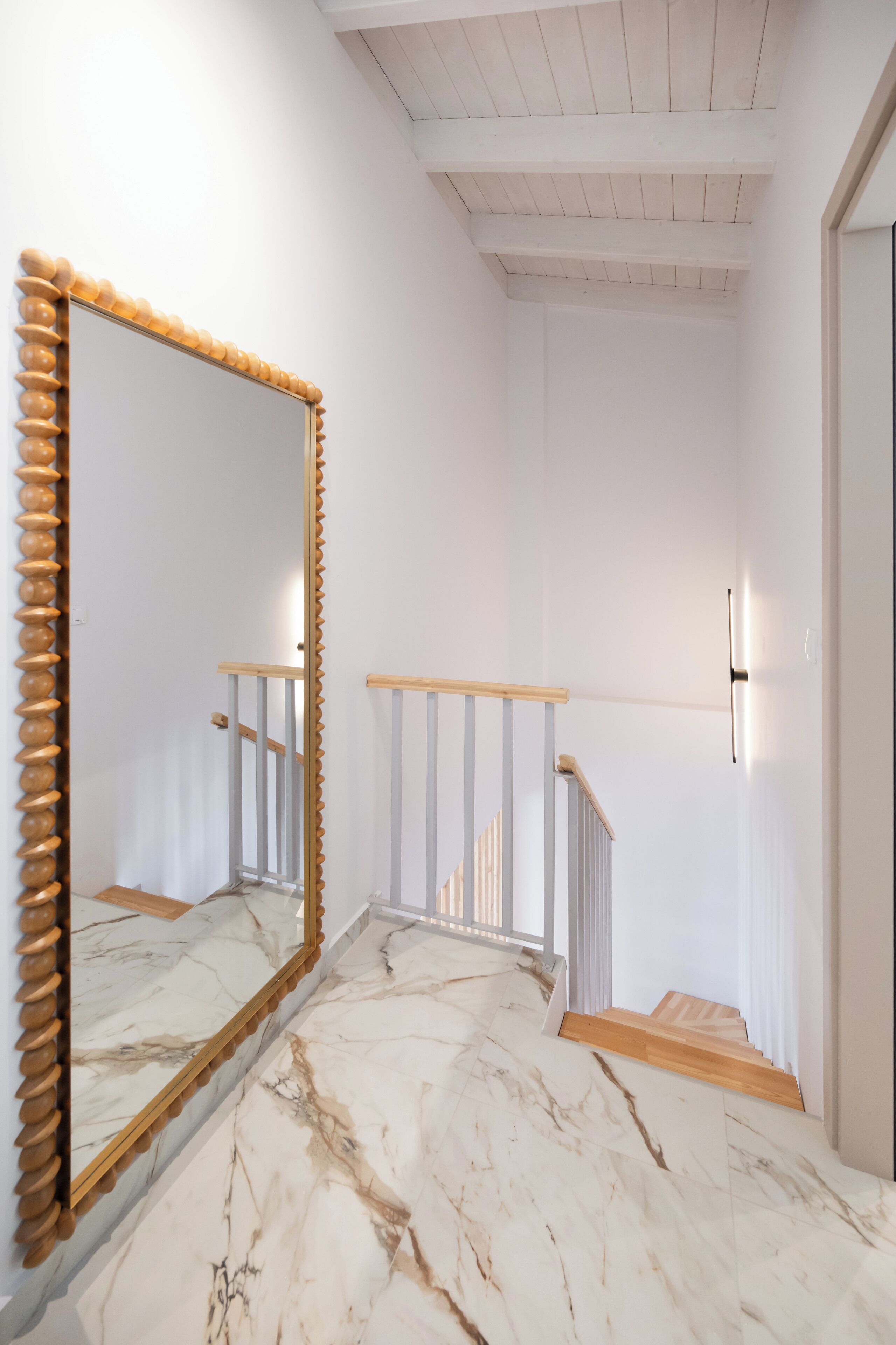A staircase with a wooden handrail and white walls.